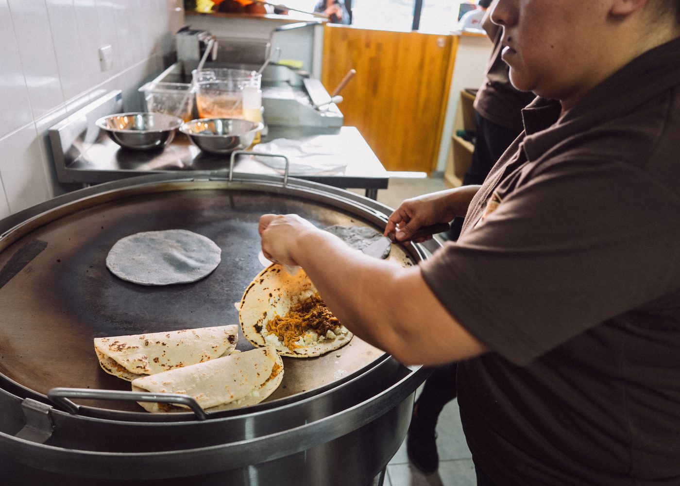 Cocinero de Kesiyos volteando tortillas de maíz en el comal